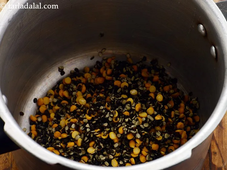 Step 4 – Transfer the chilkewali urad dal and chana dal in a pressure cooker.&nbsp;
