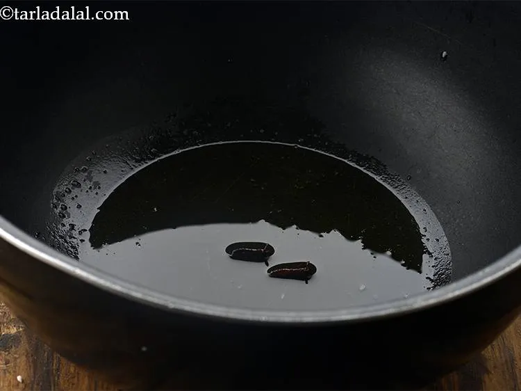 स्टेप 12 – अब हम खडे मसाले जोडेगें। सबसे पहले लौंग डालें।