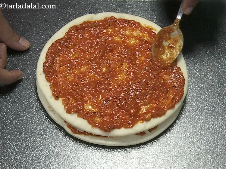 Step 17 – Spread &frac14; cup of pizza sauce.