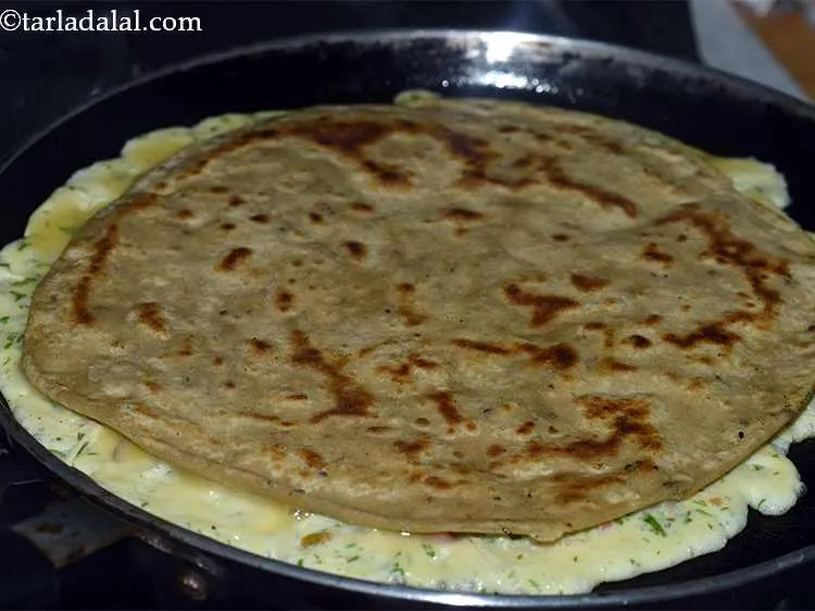 Step 25 – Place a previously prepared paratha on it. Press it gently using a flat spoon. The …