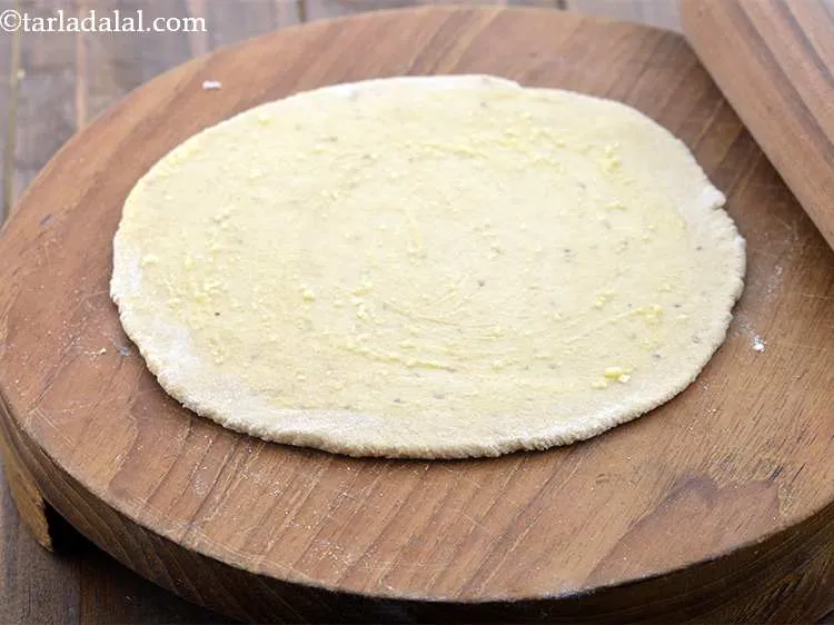 Step 10 – Spread &frac14; tsp of ghee evenly over the rolled out dough with the help of …