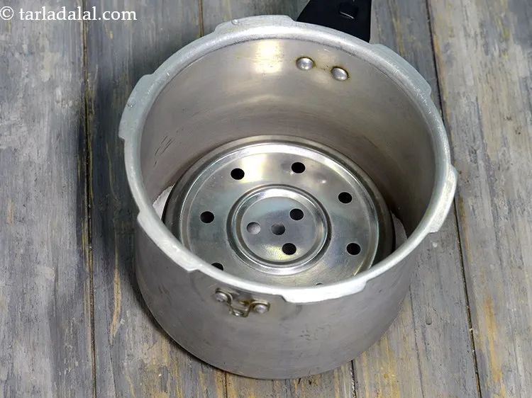 Step 3 – Follow the exact procedure of adding salt to the pressure cooker, placing a steel ring …