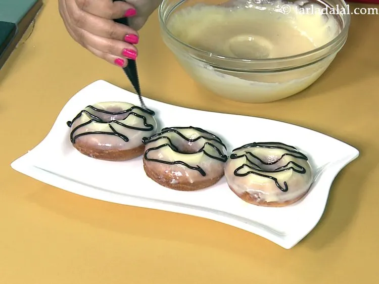 Step 50 – Spread the dark chocolate sauce on the doughnut and make a design of your choice.&nbsp;