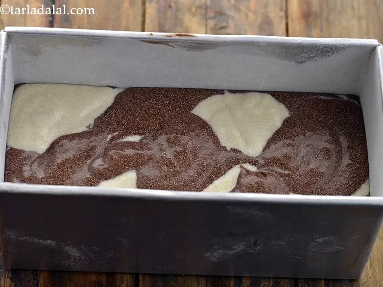 Step 19 – Take a greased and dusted loaf tin, add the vanilla sponge batter and chocolate sponge …