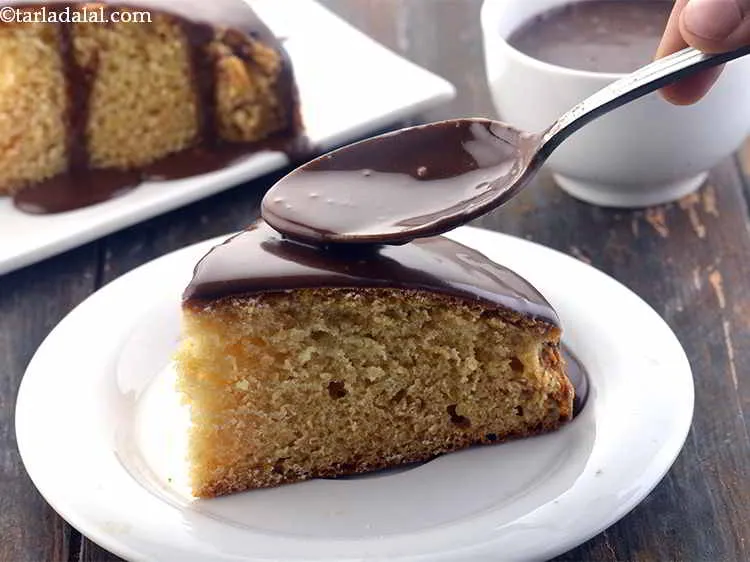 Step 23 – Cut a wedge from the&nbsp;<strong>Eggless Vanilla Sponge Cake</strong>. Pour Chocolate Glaze Icing over it. You …