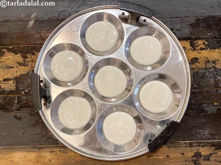 स्टेप 33 – चिकने इडली के साँचो में १ टेबल-स्पून इडली का घोल …