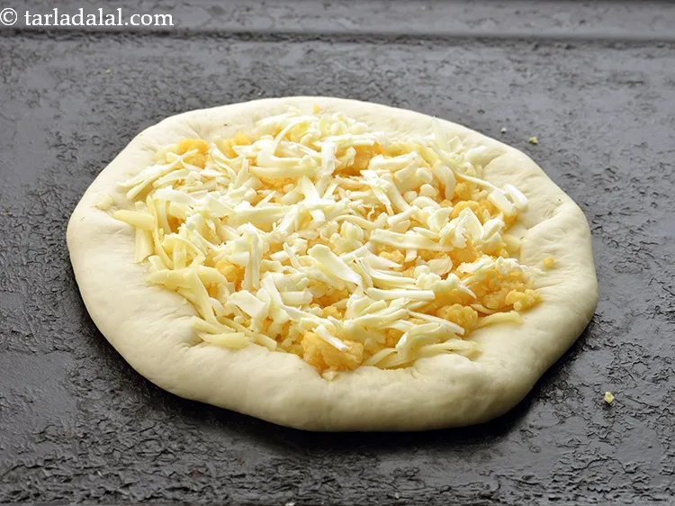 Step 19 – Sprinkle 1/4 cup of <a href="https://www.tarladalal.com/glossary-grated-processed-cheese-868i">grated processed cheese</a> evenly over it.