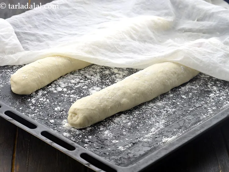 Step 24 – Place both the rolled cylindrical rolls into a dusted baking tray, cover it with a …