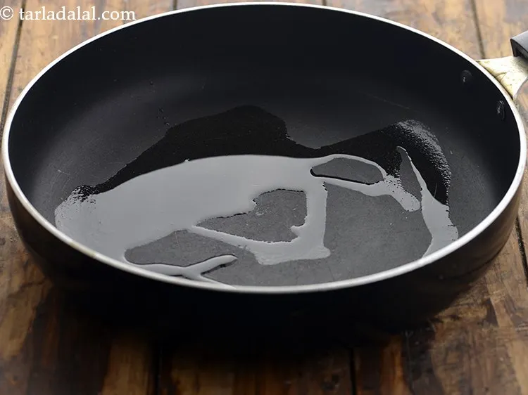 Step 14 – To prepare&nbsp;<strong><a href="https://www.tarladalal.com/recipes-for-veg-recipes-south-indian-44" target="_blank">South Indian</a>&nbsp;beans poriyal</strong>, heat oil in a broad non-stick pan.