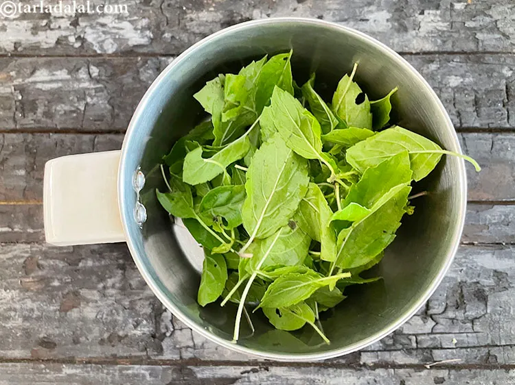 Step 7 – In a mixer put 1/2 cup <a href="https://www.tarladalal.com/glossary-tulsi-leaves-indian-basil-187i">tulsi leaves</a>. <strong>See above on details of washing …