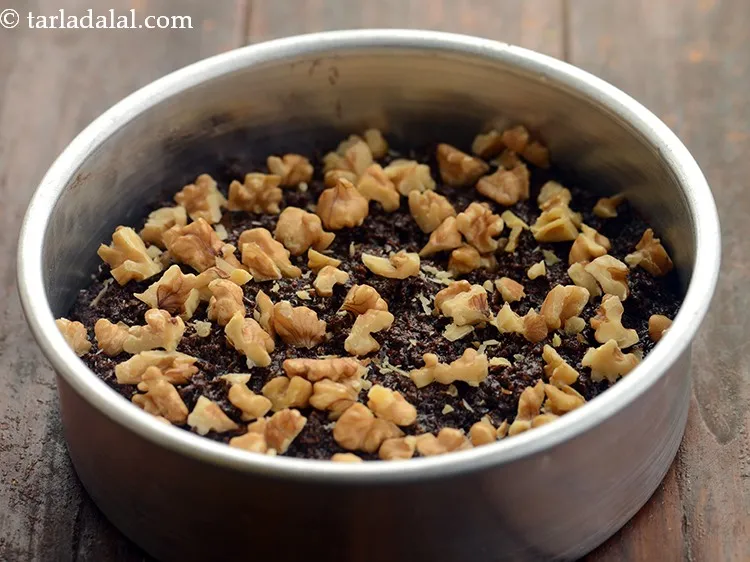 स्टेप 10 – इसके ऊपर समान रूप से अखरोट डालें। आप हाथ से …