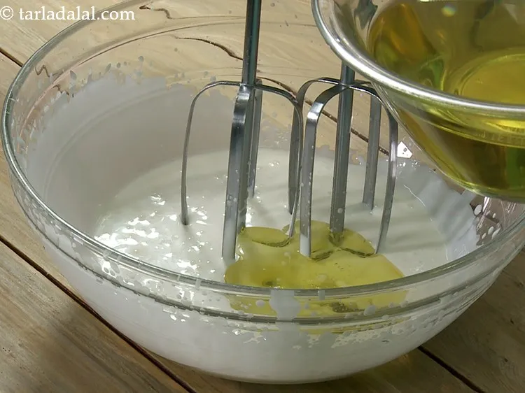 स्टेप 4 – ताजे क्रीम-कंडेंस्ड मिल्क मिश्रण को लगातार चलाते हुए धीरे-धीरे तेल …