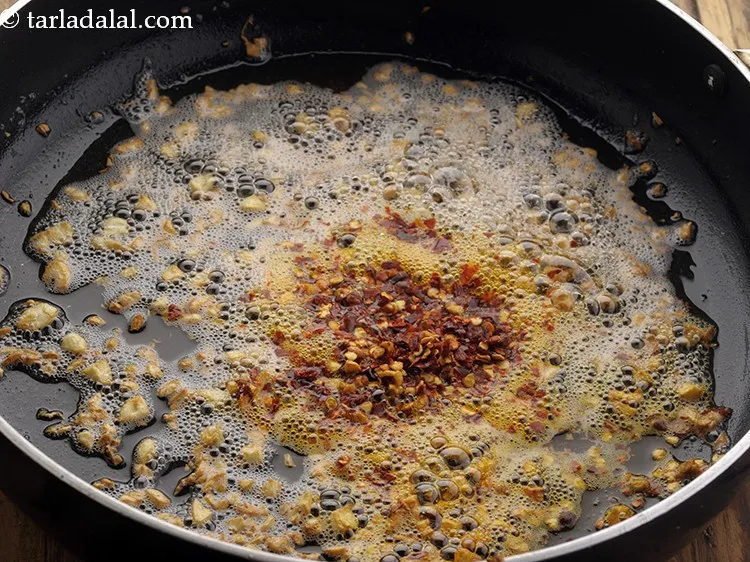 स्टेप 4 – १ टेबल-स्पून सूखी लाल मिर्च के फ्लैकस् डालें।