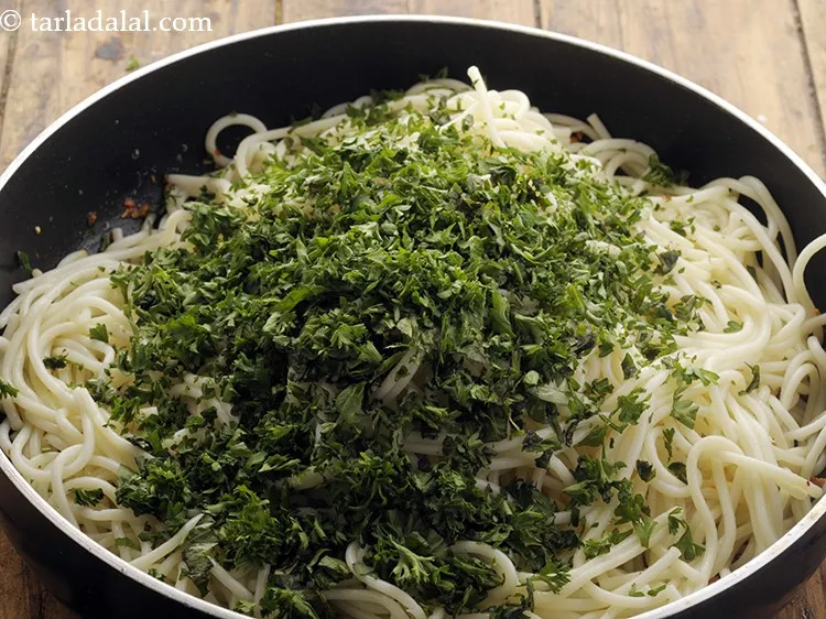 स्टेप 8 – अजमोदा डालें। अजमोद और बेसिल हमारी <strong>गार्लिक स्पैगेटी</strong> को रंग …