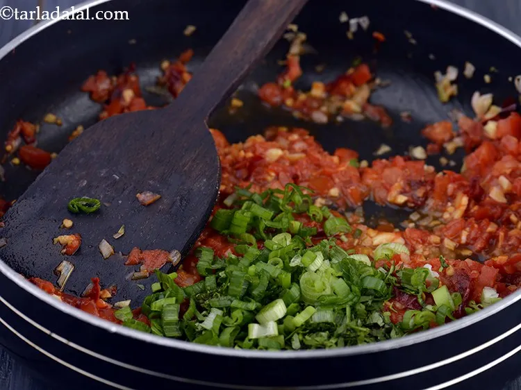 Step 15 – Add the spring onion greens. These add a great mouthfeel to the <strong>Lehsuni Tomato Chutney</strong>.