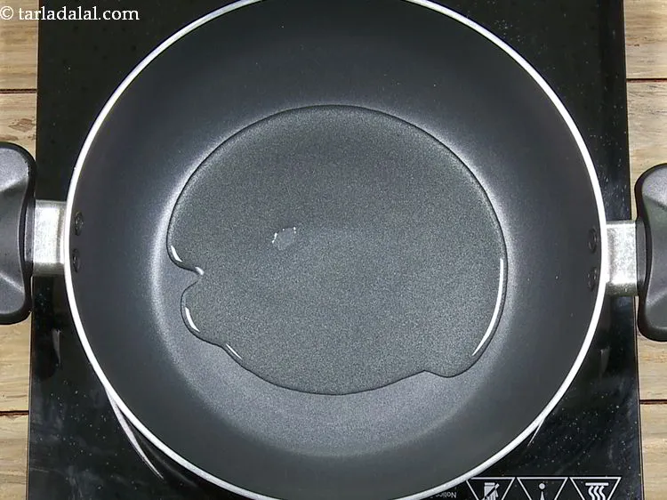 Step 14 – To temper the chilli-garlic rice, heat the oil in a broad non-stick pan.