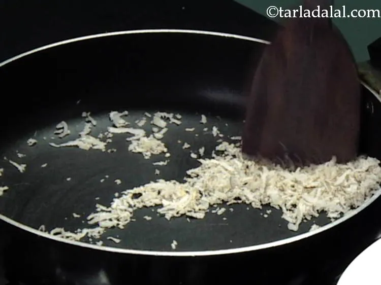 स्टेप 2 – उसी पैन में कसा हुआ सूखा नारियल डालें और धीमी …