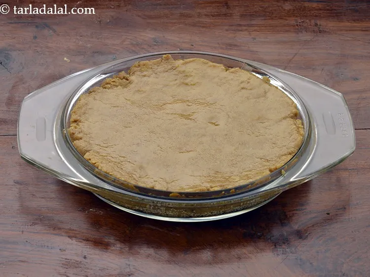 Step 11 – Pour the mixture into the greased thali with poppy seeds while still warm and spread …