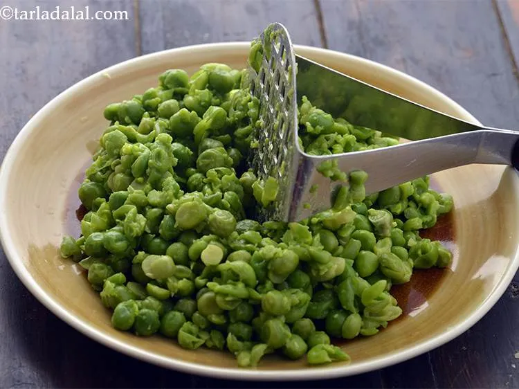 स्टेप 3 – एक आलू मैशर की मदद से हरे मटर को हल्का …