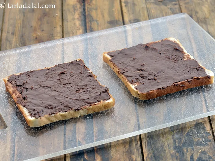 Step 5 – Then spread &frac12; tbsp of&nbsp;<a href="https://www.tarladalal.com/glossary-nutella-1288i">nutella hazelnut chocolate spread</a> evenly on each bread slice.