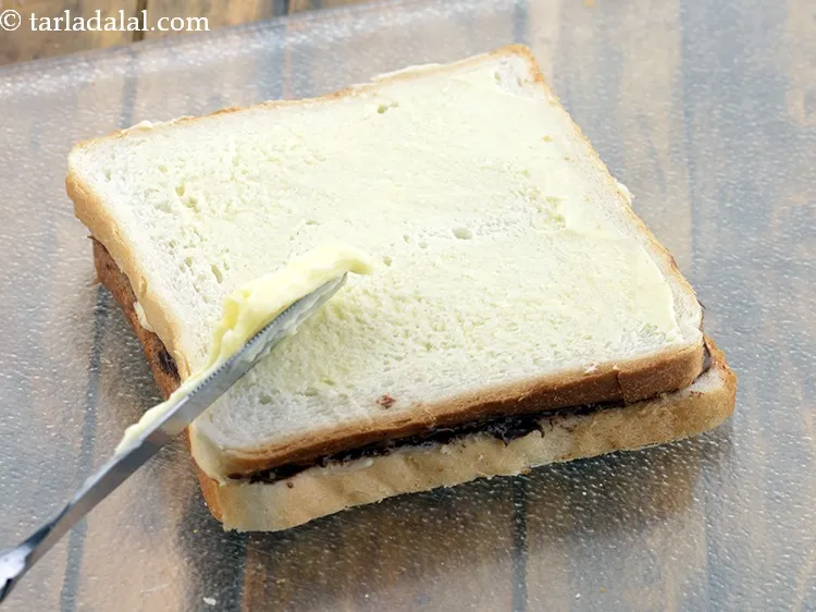 Step 8 – Brush &frac12; tsp of <a href="https://www.tarladalal.com/glossary-butter-makhan-233i">butter</a>&nbsp;on top of the bread.