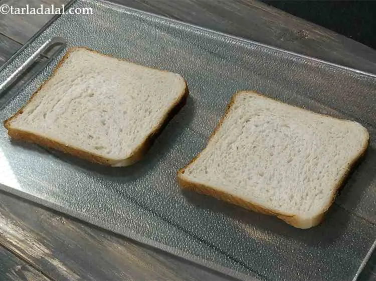 Step 2 – To make Grilled Tomato and Cheese Sandwich, first place 2 bread slices on a clean, …