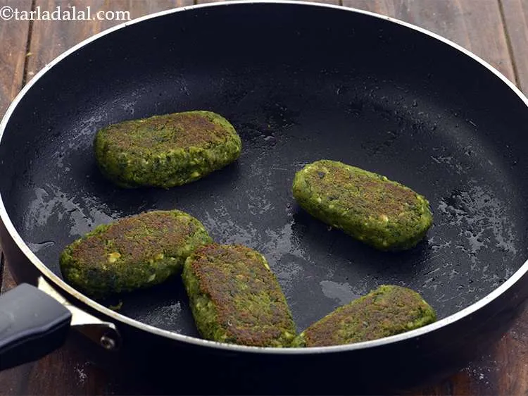 Step 19 – Use a wooden spatula to flip the tikkis one by one.&nbsp; Now drizzle 1 tsp …