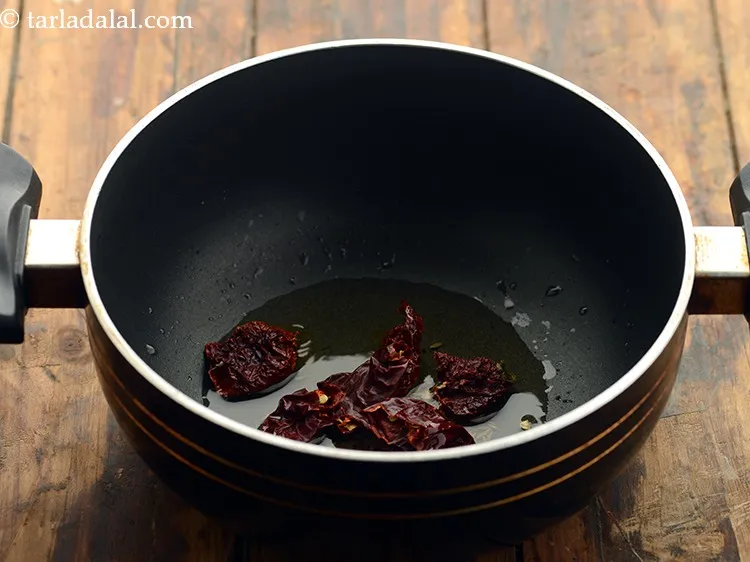 Step 12 – When the seeds crackle, add the dry red chillies.