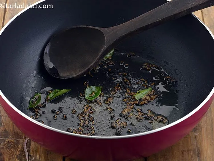 स्टेप 7 – जब बीज चटकने लगे, तब हींग और कडीपत्ते डालें और …