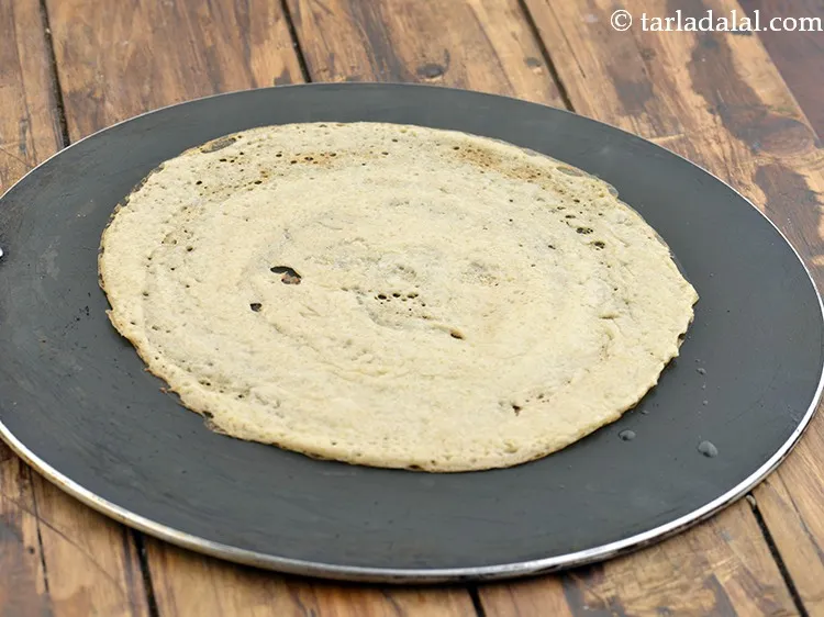 Step 26 – Smear 1 tsp of ghee over it and along the edges and cook on a …