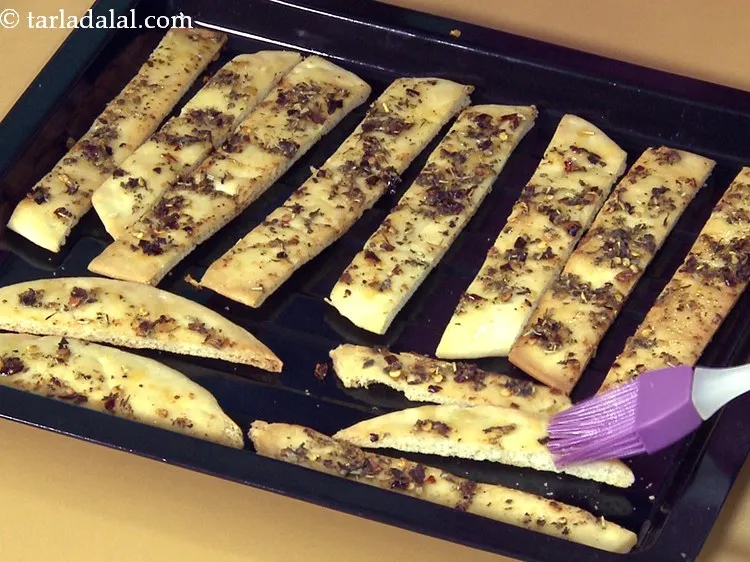 Step 17 – Lightly brush the hot pizza strips with a little <a href="https://www.tarladalal.com/glossary-olive-oil-451i">olive oil</a>.