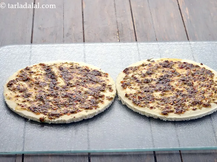 Step 14 – Brush equal quantities of the prepared topping on both the pizza bases and spread it …