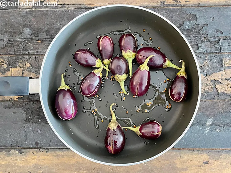 Step 31 – When the seeds crackle, add the brinjals.
