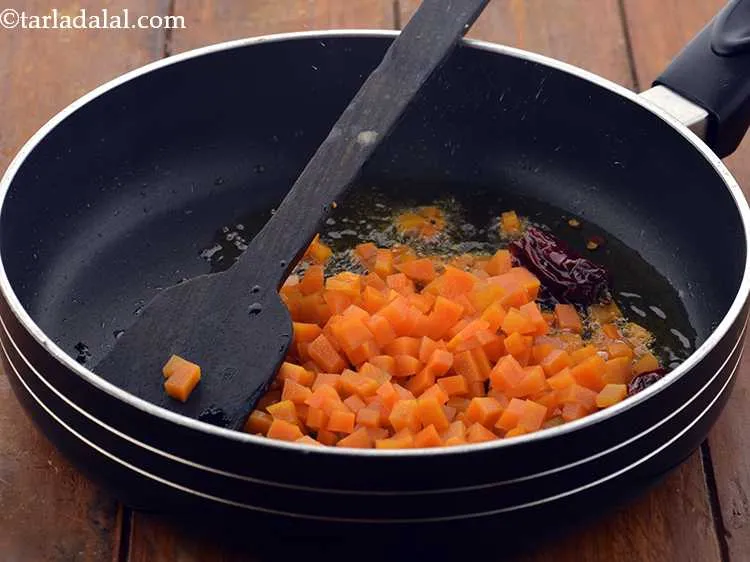 Step 7 – When the seeds crackle, add the carrot.