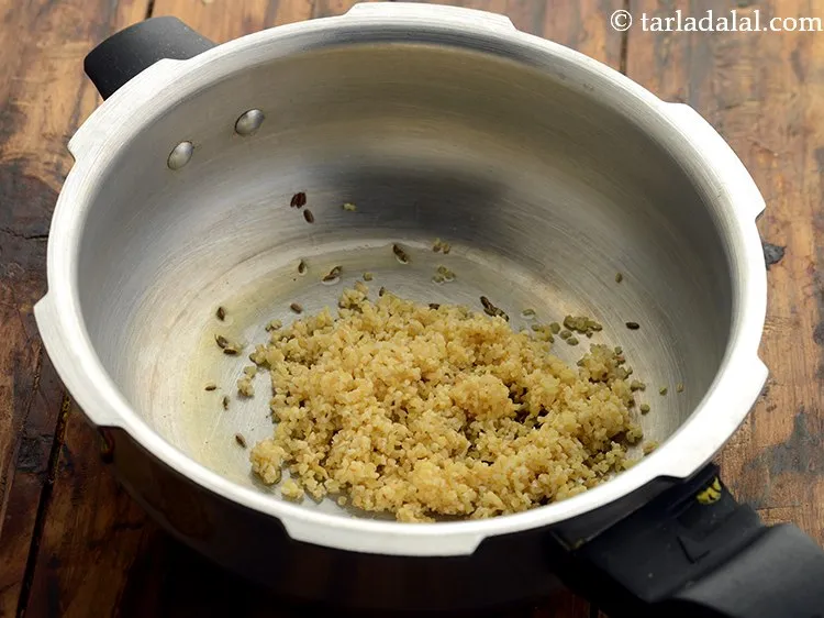 Step 8 – When the cumin seeds crackle, add the washed and drained&nbsp;bulgur wheat.