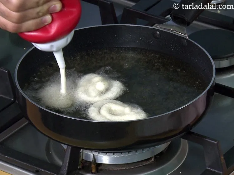Step 22 – Press the bottle / cloth to form a coil shaped <strong>jalebi</strong>, starting from the inside …