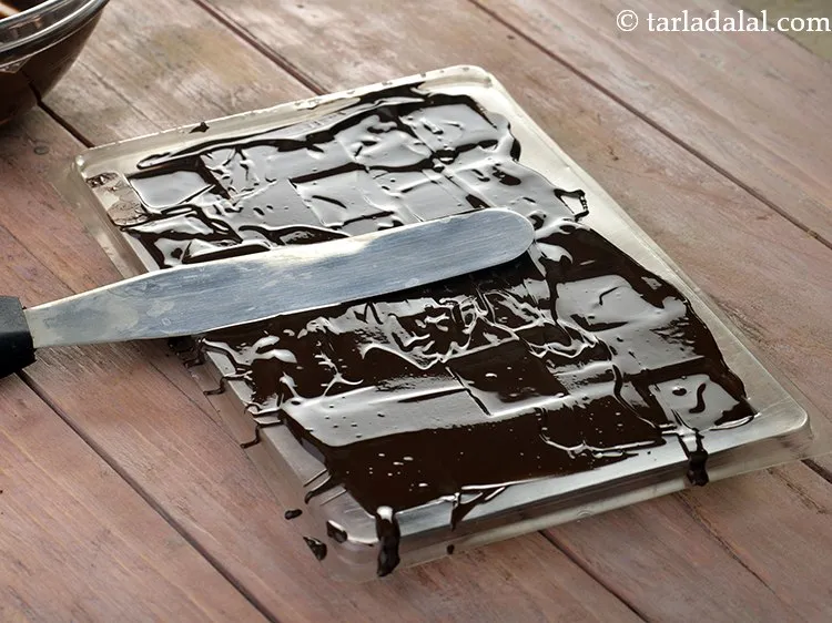 Step 26 – Fill the depressions with melted chocolate in the chocolate mould using a tablespoon and tap …