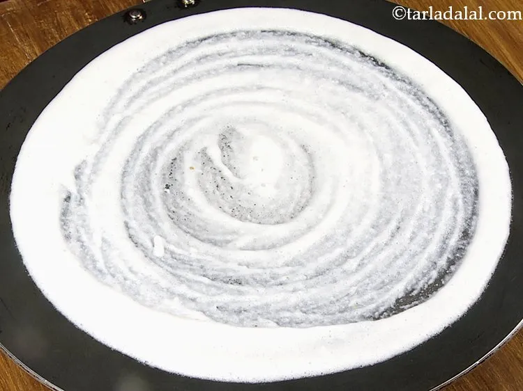 Step 12 – Pour a ladleful of the batter on the tava (griddle) and spread in a circular …