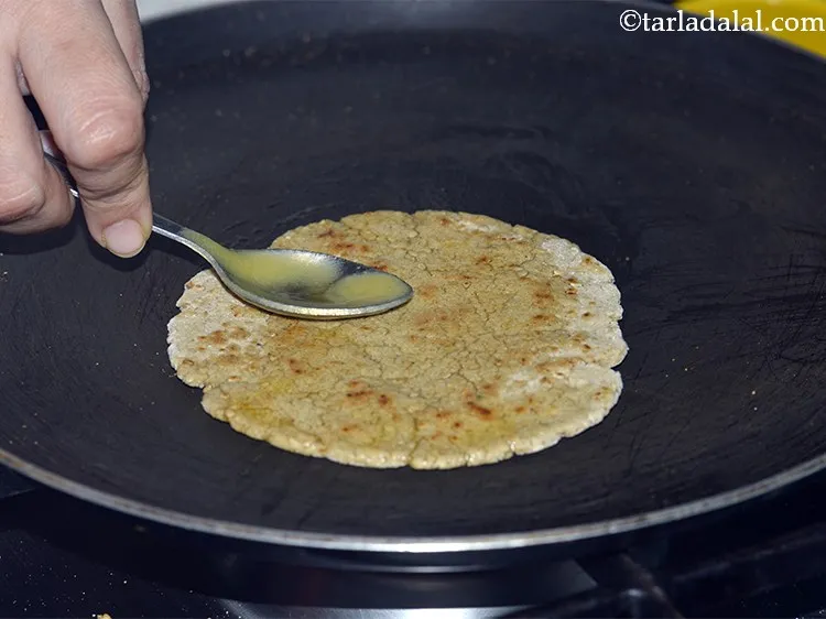 Step 19 – Lower the flame and apply &frac12; tsp ghee on each side.