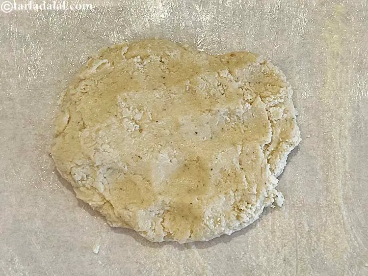 Step 16 – Transfer the kaju mixture onto a greased butter paper. We have put the butter paper …