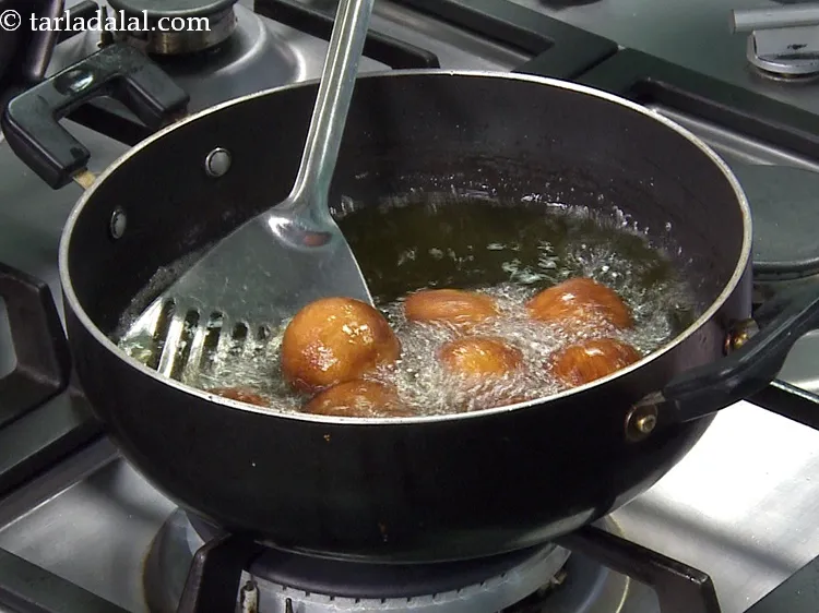 Step 28 – While frying, keep turning the kala jamuns at intervals to prevent the bottom from touching …