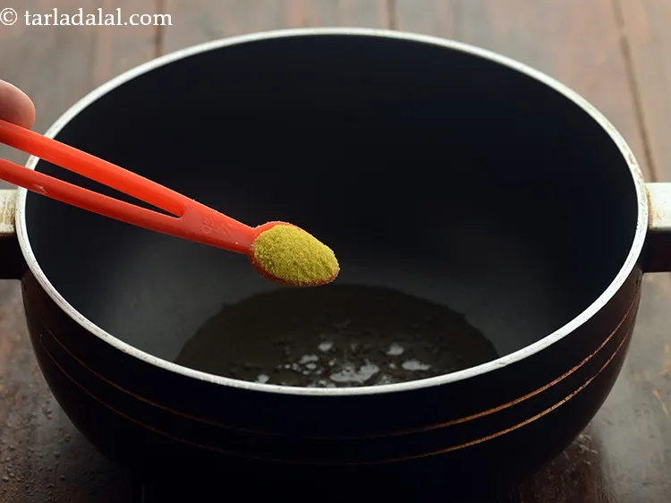 Step 4 – When the seeds crackle, add the asafoetida.