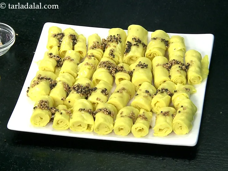 Step 30 – Pour the tempering over the&nbsp;<strong>khandvis</strong>&nbsp;with the help of a spoon.