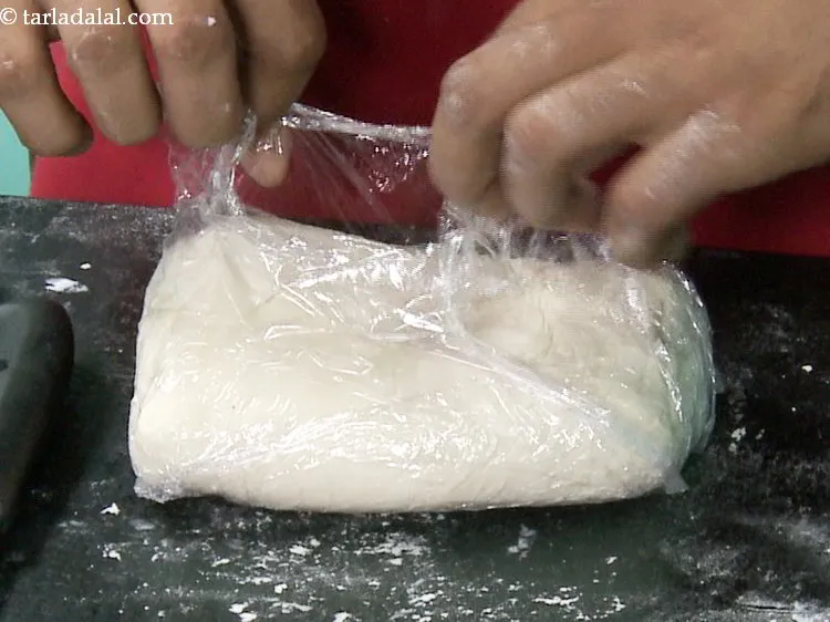 Step 27 – Remove the cling wrap and dust the dough with flour.