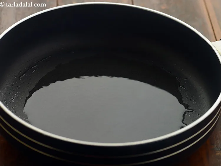 Step 14 – To temper the moong dal for <strong>moong dal kachori</strong>, heat the oil in a broad …