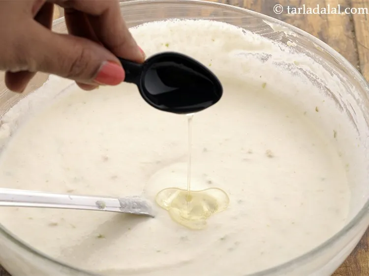 स्टेप 16 – तेल डालें। इससे <strong>ढोकले</strong> का घोल अधिक मुलायम हो जाएगा।
