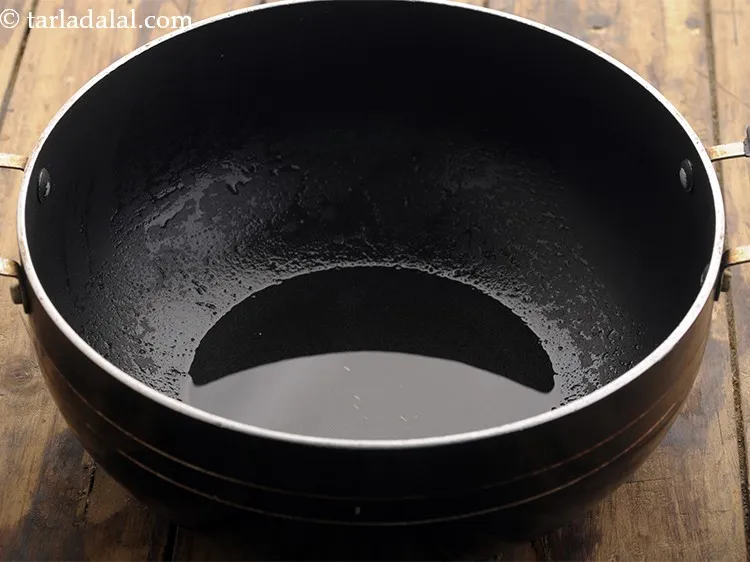 Step 13 – To temper, <strong>Khatta Moong</strong> heats the oil in a deep non-stick kadhai.&nbsp;
