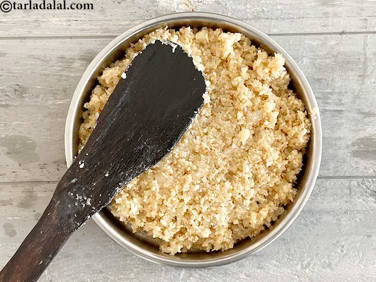 Step 21 – Transfer the mixture into a greased thali&nbsp;and spread it evenly using a flat ladle.