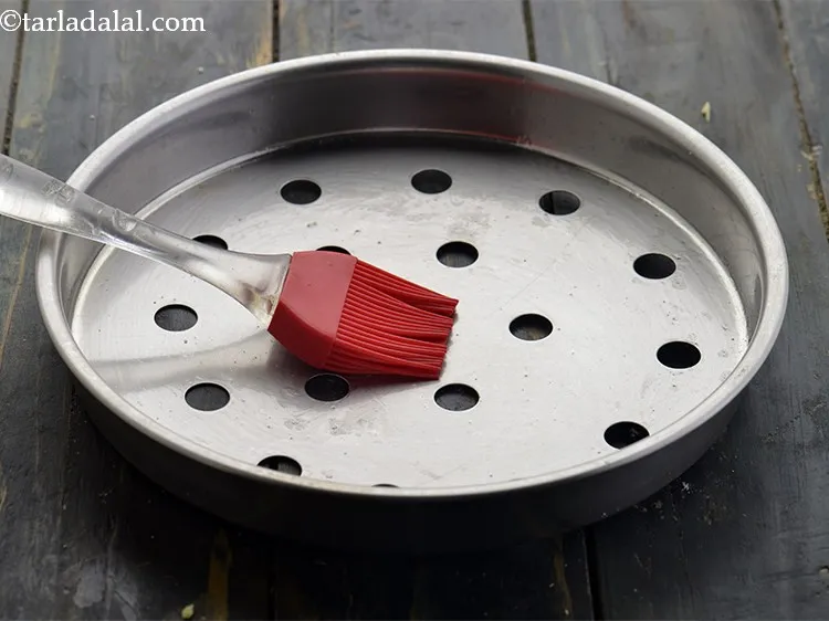 Step 20 – Grease a sieve with oil using a brush. This prevents the muthia from sticking to …