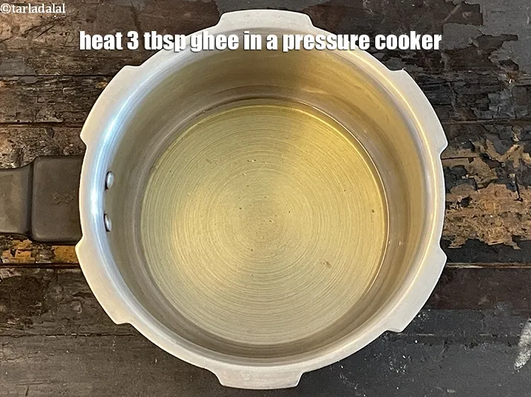 Step 3 – To make <strong>pressure cooker lapsi</strong>, heat&nbsp;<meta charset="UTF-8" />3 tbsp&nbsp;<a href="glossary-ghee-245i">ghee</a>&nbsp;in a pressure cooker.